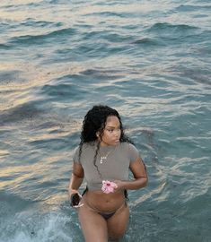 a woman standing in the water holding a flower