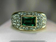 a ring with a green stone surrounded by white and gold pave diamonds on it