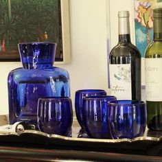 blue glassware and wine bottles sit on a shelf next to a bottle of wine