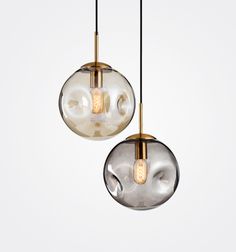 two glass balls hanging from the ceiling with lights attached to them and one light on each side