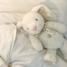 a white stuffed animal laying on top of a bed