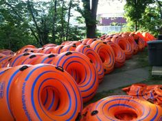 many orange and blue tubes are lined up on the ground in front of some trees