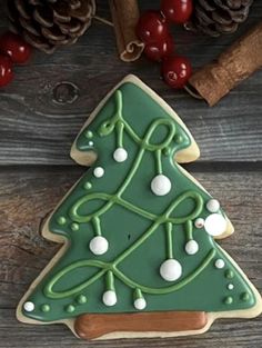 a decorated christmas tree cookie sitting on top of a wooden table next to cinnamon sticks