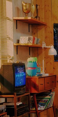 a television sitting on top of a wooden desk next to a shelf filled with books