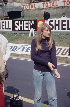 a woman standing on the side of a road next to a man holding a cell phone