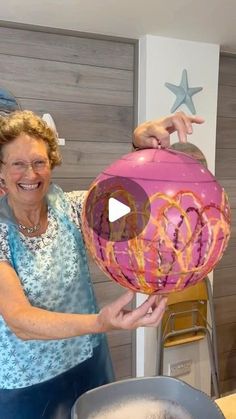 an older woman holding up a paper lantern in front of a pan filled with liquid