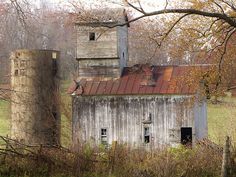 an old barn with rusted tin roof and two silos