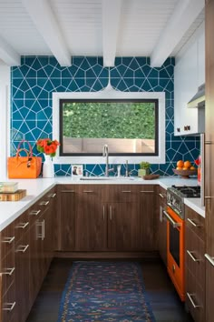 a kitchen with blue and orange tiles on the walls, wood cabinets, and an area rug