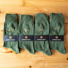 five pairs of green socks with gold lettering on them sitting on a wooden table top