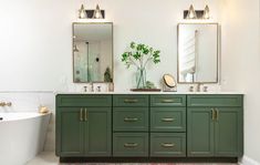 a bathroom with green cabinets and two mirrors on the wall next to a bathtub