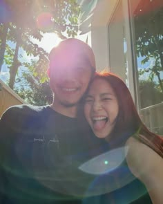 a man and woman are smiling for the camera with their arms around each other in front of a building