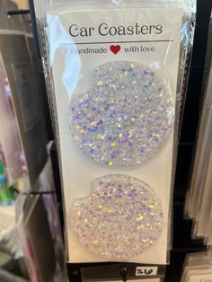 car coasters with white and silver glitter on them in a store display case for sale