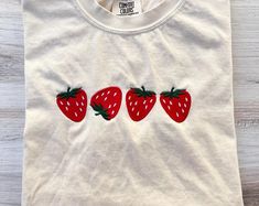 three strawberries embroidered onto a white t - shirt