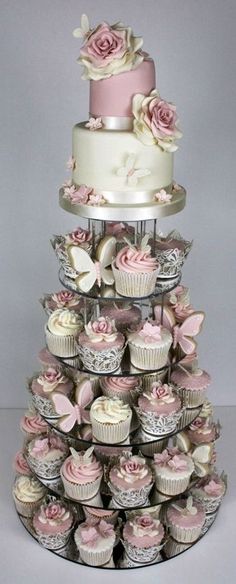 a three tiered cake with cupcakes on the bottom and pink roses on top