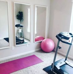 a room with exercise equipment, mirrors and yoga mats on the floor in front of it