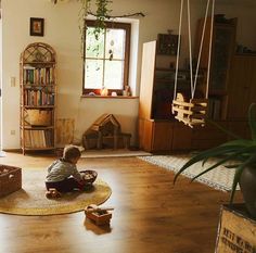 a small child sitting on the floor in a living room with bookshelves and toys