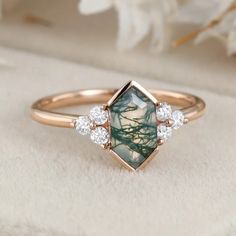 a close up of a ring with a green stone in the middle and three diamonds on it