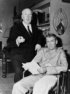 black and white photograph of two men sitting in a living room with one pointing at something