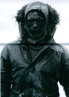 a man wearing a jacket and hat standing in the snow