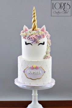 a three tiered cake with a unicorn's face on top and the words sopiia written in gold