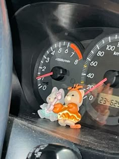 a car dashboard with gauges and an animal figurine