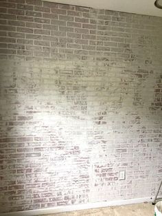 a white brick wall in an empty room with a mop and bucket on the floor