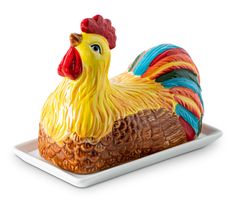 a colorful rooster figurine sitting on top of a white plate