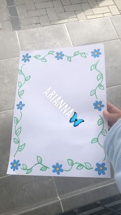 a person holding up a piece of paper with the word nirvana on it and blue flowers