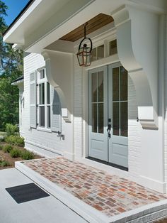 a white house with two doors and brick walkway