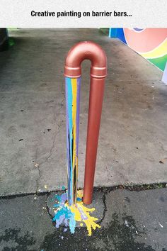 an orange and blue umbrella stand on the sidewalk with paint splattered all over it