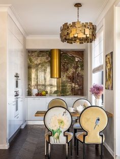 a dining room table with four chairs and a chandelier hanging from the ceiling