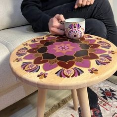 a person sitting on a couch with a coffee cup in their hand and a colorful flower design on the table