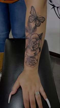 a woman's arm with a butterfly and rose tattoo on the left side of her hand