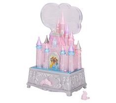 a pink castle with a clock on top and some princess figurines around it