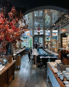 the interior of a restaurant with tables, chairs and vases on display in front of it