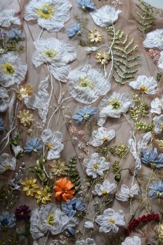 the fabric is covered with many different flowers and leaves, including daisies or anemones