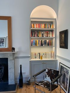 a living room with a chair and bookshelf filled with lots of books next to a fireplace