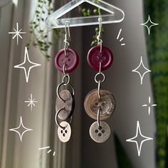 a pair of earrings hanging from a hook on a window sill with stars in the background