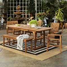 an outdoor dining table and chairs with potted plants in the background