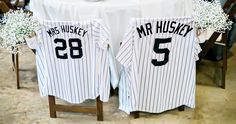 the table is set up with two baseball jerseys on it and baby's breath flowers