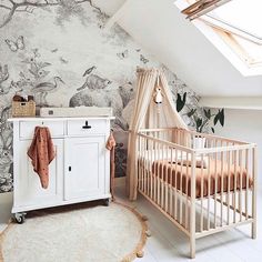 a baby's room with a crib, dresser and wallpaper