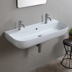 a bathroom sink sitting under a mirror next to a table with a potted plant on it