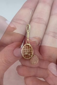 a person holding a tennis racket charm in their hand