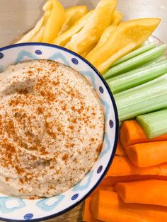 a bowl of dip surrounded by carrots and celery