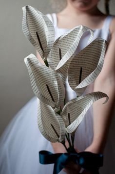 a woman holding a bouquet of flowers made out of book pages