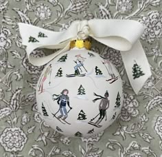 a white ornament with skiers on it and a bow around the neck