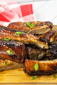 some meat is sitting on a cutting board with green garnishes around it