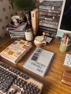 a computer keyboard sitting on top of a wooden desk next to a pile of books