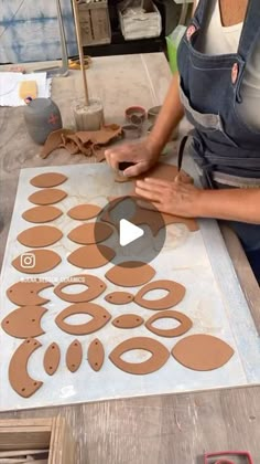 a woman is making paper cut outs on a table