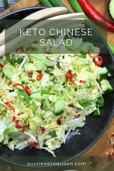 a bowl filled with lettuce and red peppers next to some chopsticks